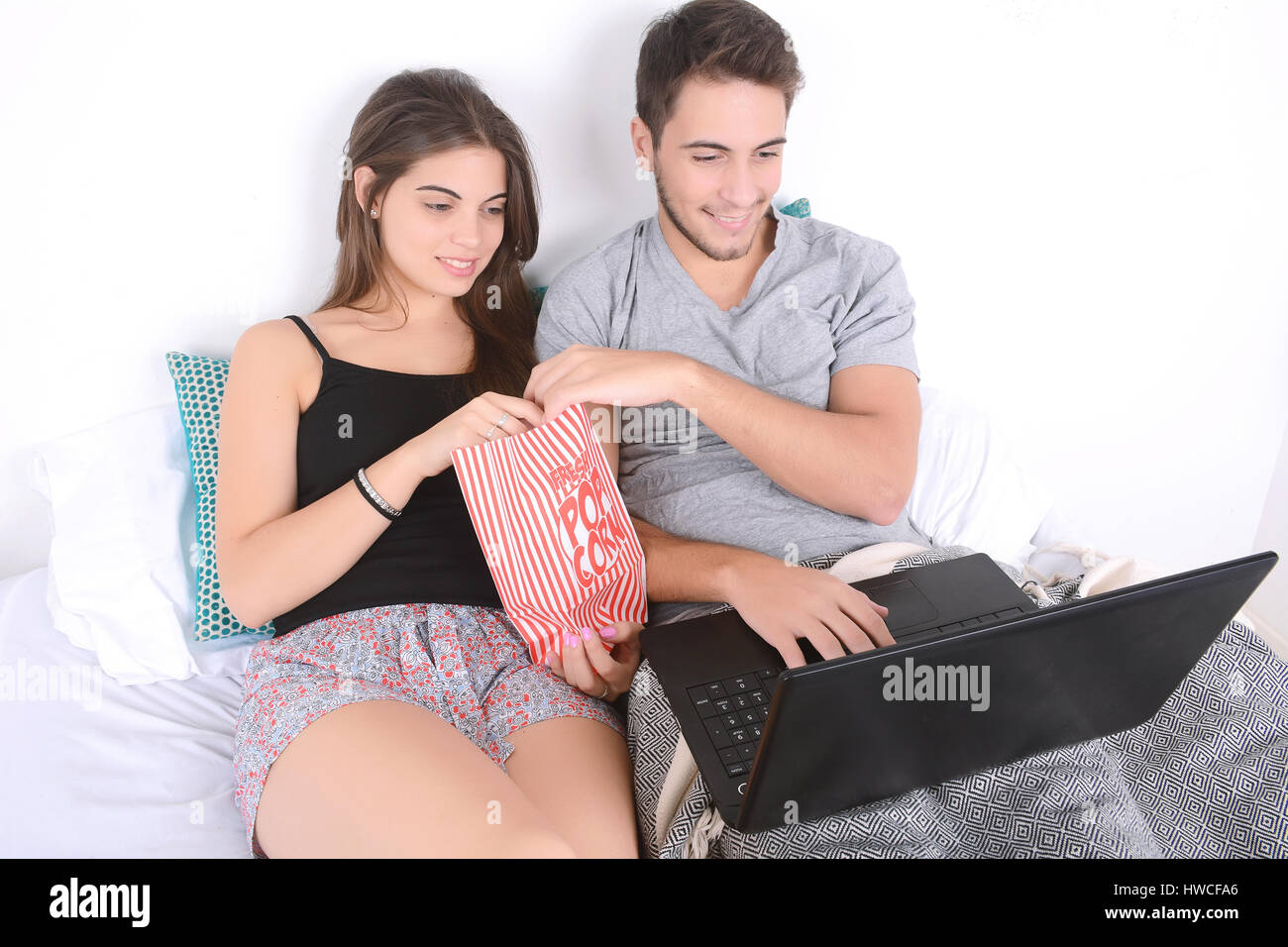 Schöne junge Paar mit Laptop und Filme im Bett. Im Innenbereich. Stockfoto