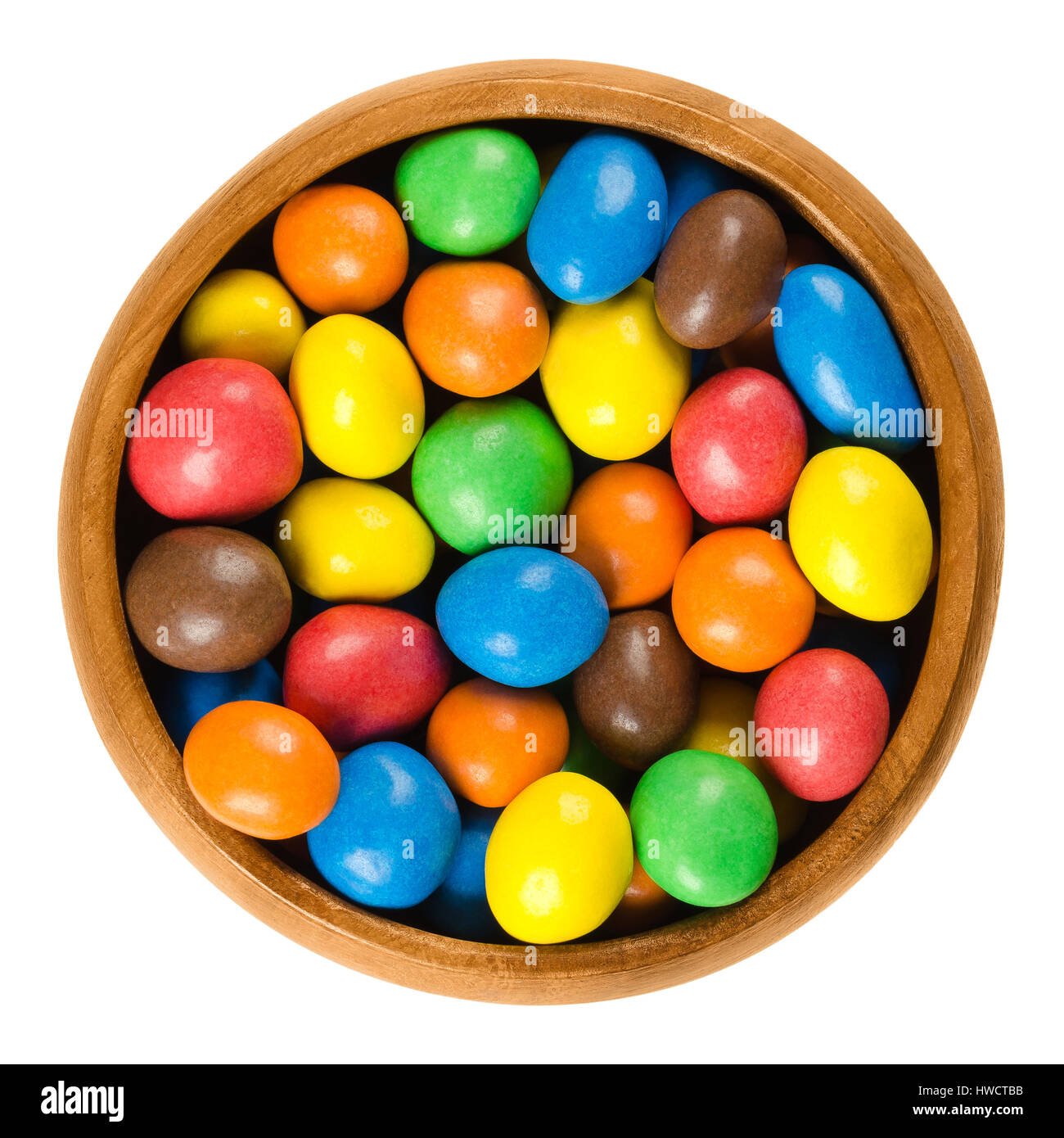 Bunte Pralinen Erdnuss in Holzschale über weiß. Erdnüsse in Milchschokolade mit Candy Shell in verschiedenen Farben beschichtet. Makro-Foto. Stockfoto