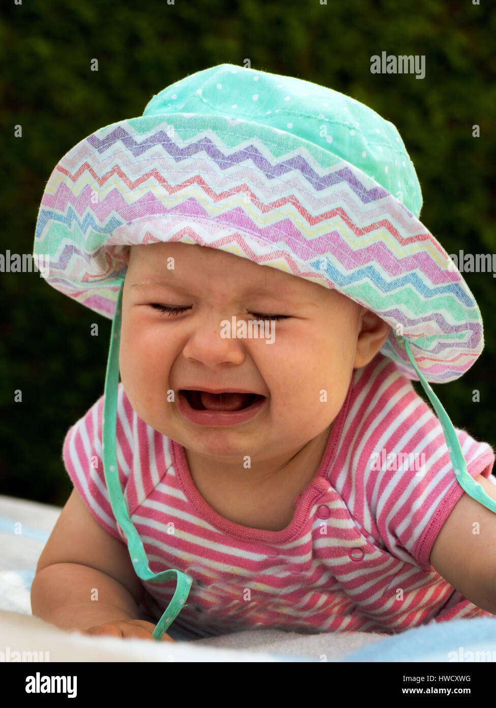 Schreiendes Baby liegt auf einer Wiese und ist traurig, Weinendes Baby Liegt Auf Einer Wiese Und ist traurig Stockfoto