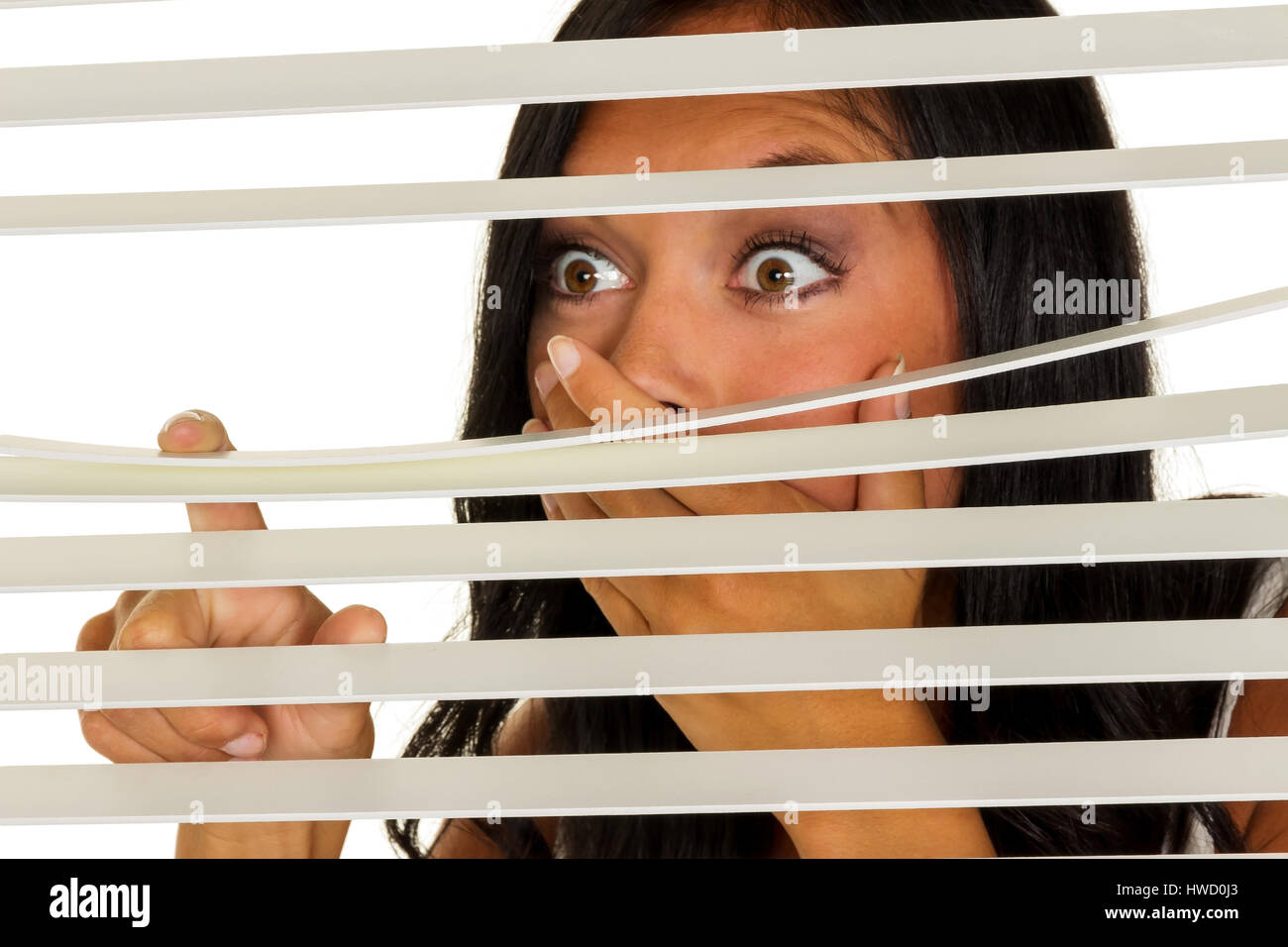 Eine junge Frau beobachtet etwas durch die Jalousie von ihrem Fenster, Eine Junge Frau Beobachtet Etwas Durch Die Jalousie Ihres Fensters Stockfoto