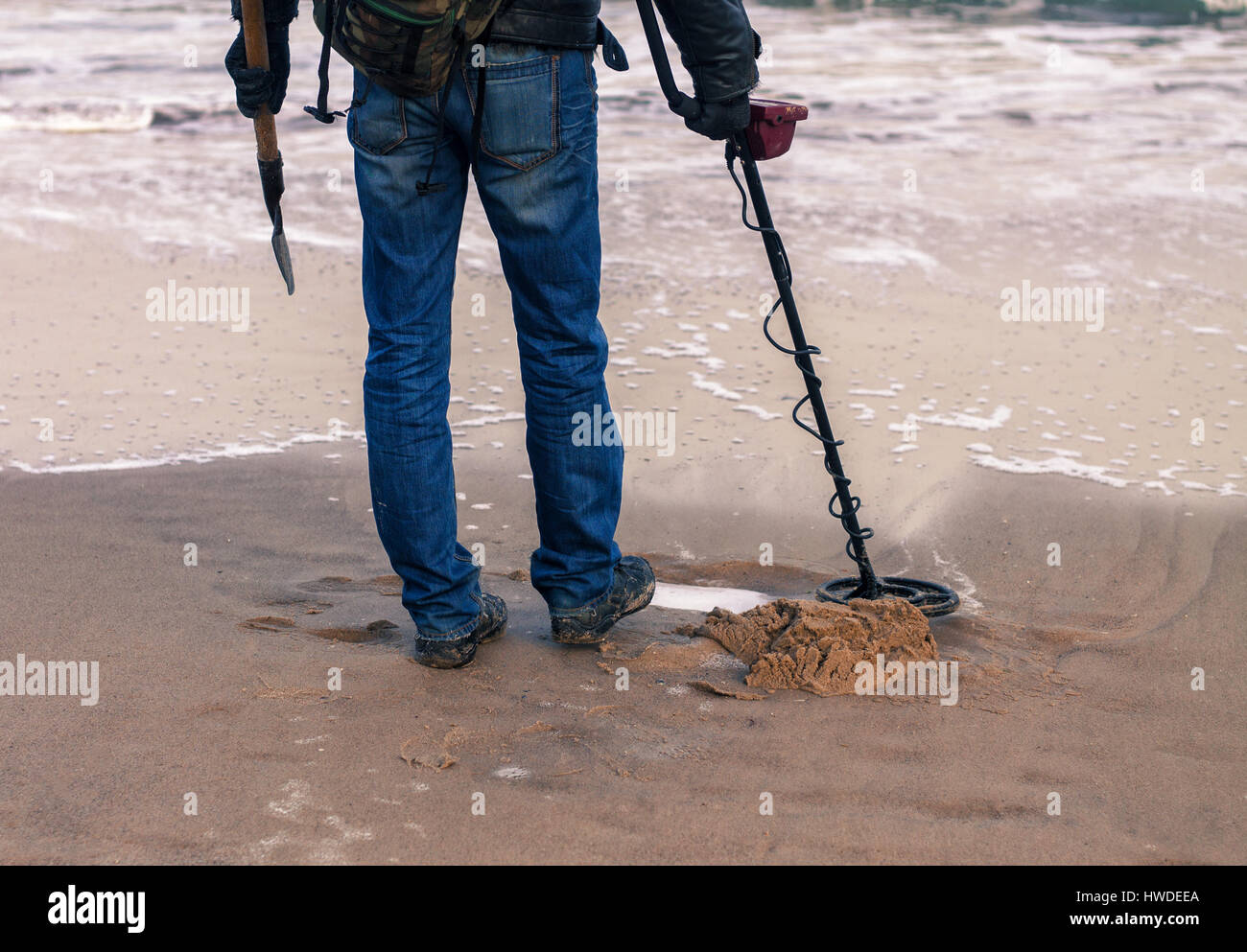 Mann mit einem Metall-Detektor für Metall oder verlorenen Schatz am Sandstrand suchen. Er hat Showel in der hand Stockfoto
