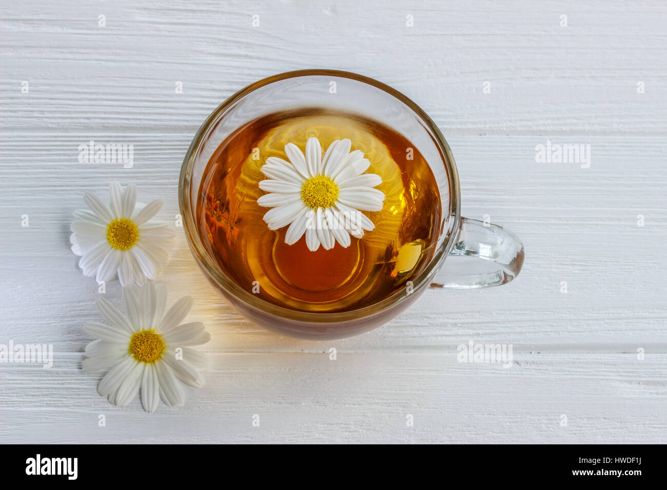 Tasse Kamillentee mit Kamillenblüten auf einem Holztisch Stockfoto