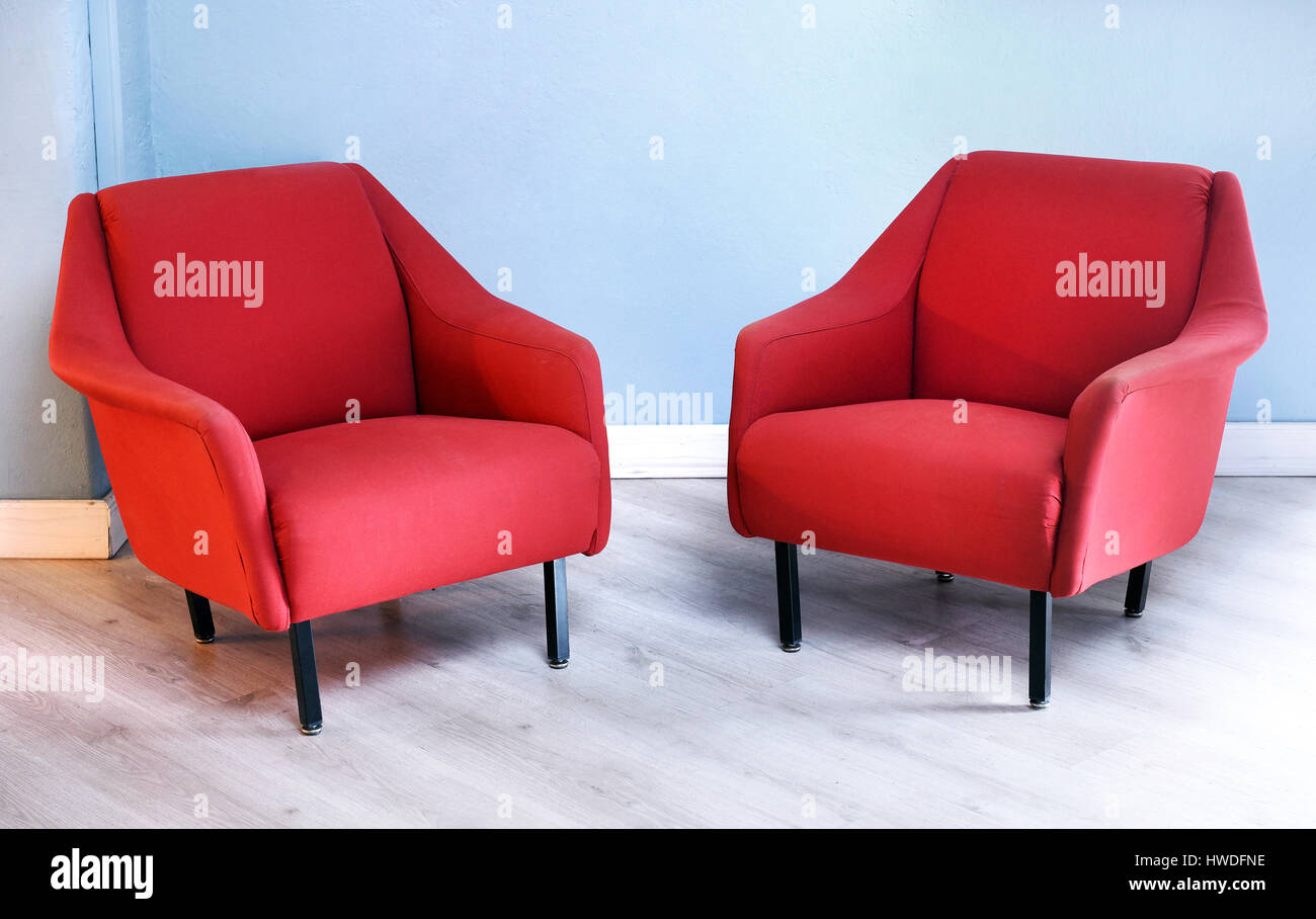 Stillleben mit paar Plüsch rot Vintage Sessel mit schwarzen Beinen in Zimmer mit Holzboden und hellen blauen Wänden Möbel Stockfoto