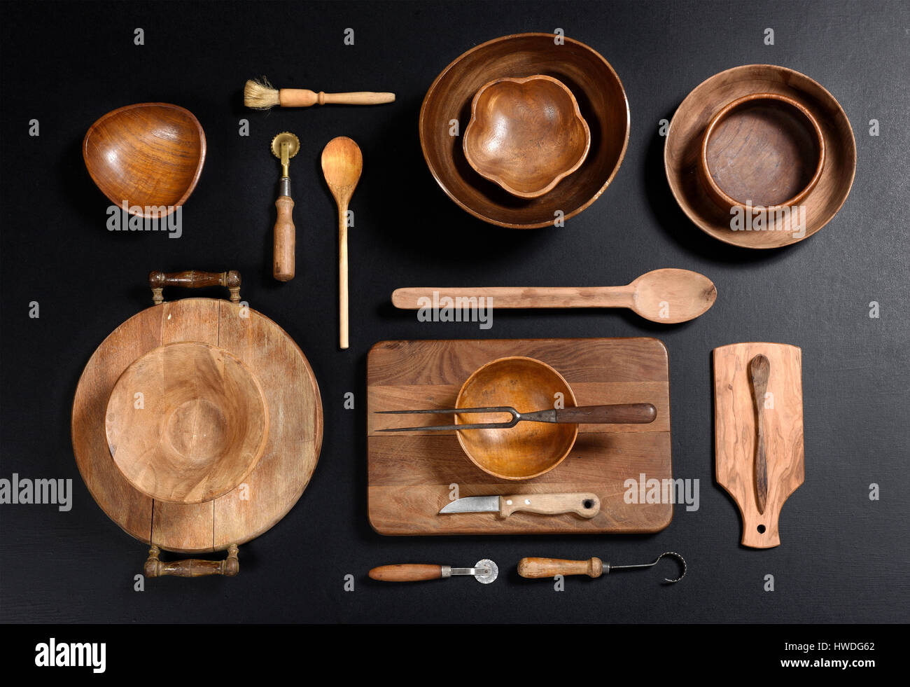 High Angle Stillleben View Sammlung von Holz Küche-Objekten - Holz Schalen schneiden Bretter, Löffel und andere Utensilien auf dunklen schwarzen Hintergrund Stockfoto