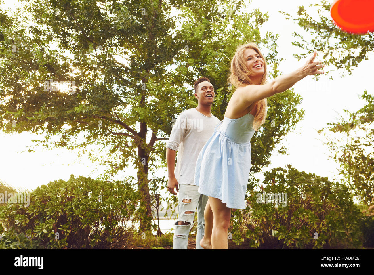 Junge Frau und Mann werfen fliegende Scheibe im park Stockfoto
