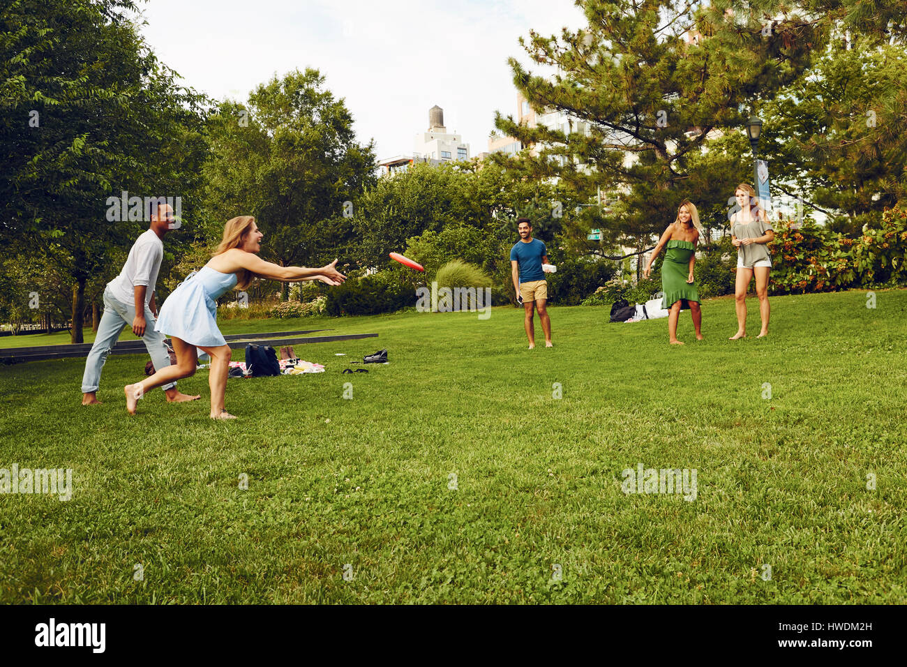 Fünf Erwachsene Freunde spielen mit fliegenden Scheibe im park Stockfoto