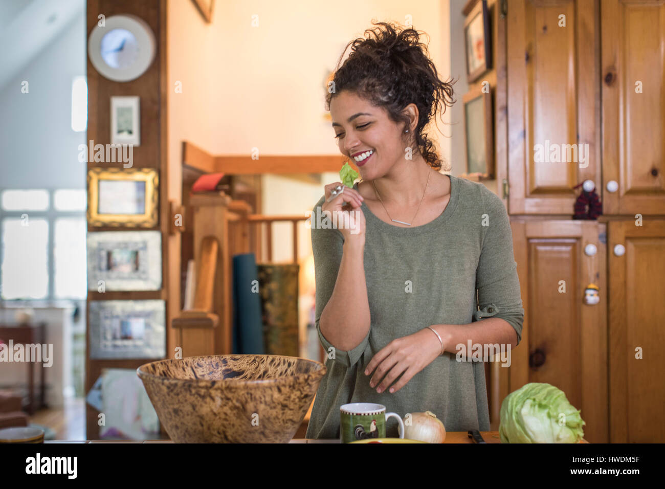 Junge Frau am Küchentisch essen Salat Salat vorbereiten Stockfoto