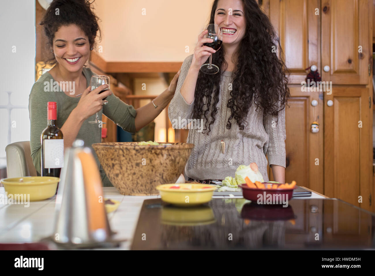 Zwei Freundinnen Salat vorbereiten und Lachen am Küchentisch Stockfoto