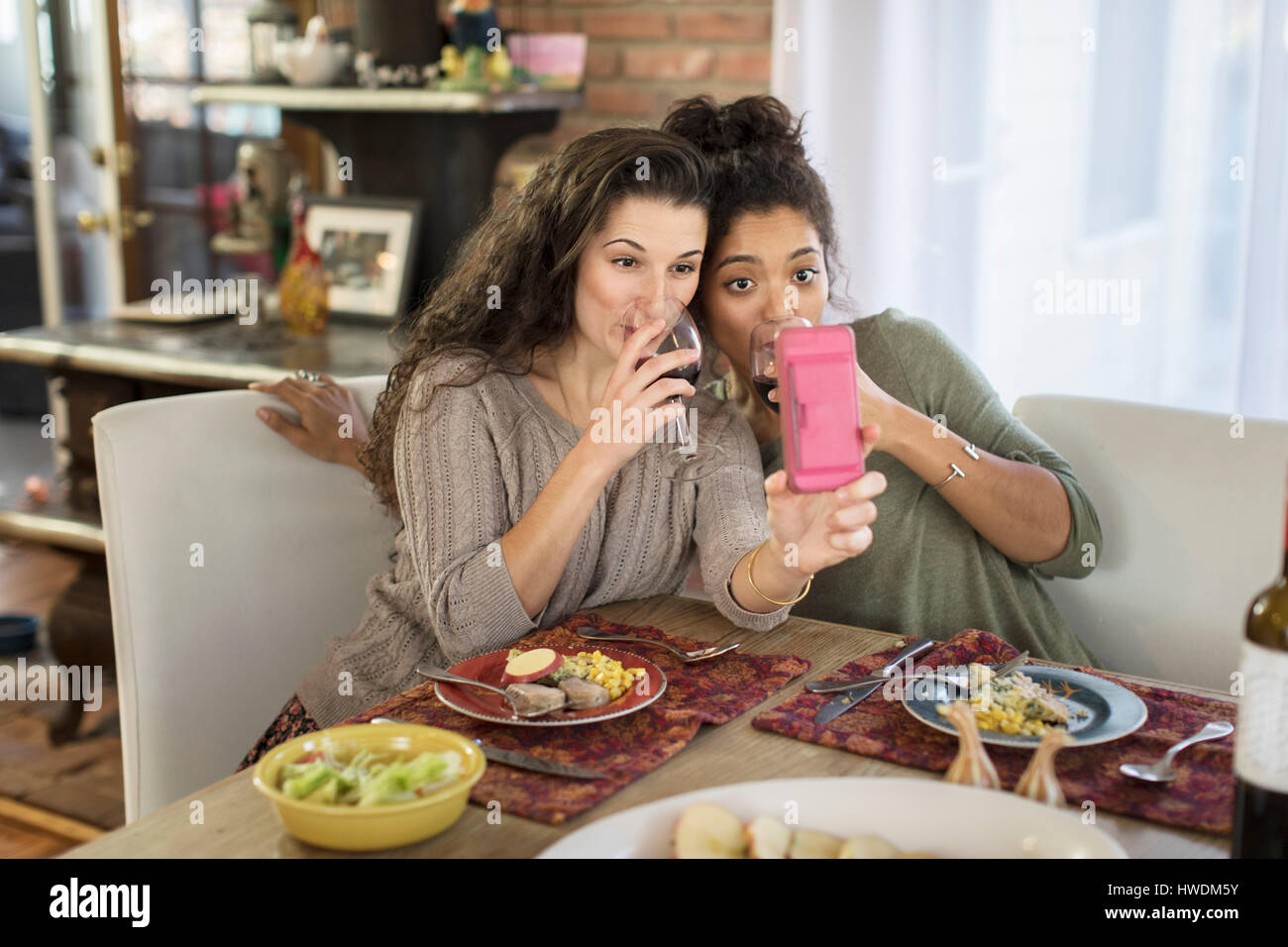 Zwei junge Frauen Freunde nehmen Selfie trinken Rotwein am Küchentisch Stockfoto