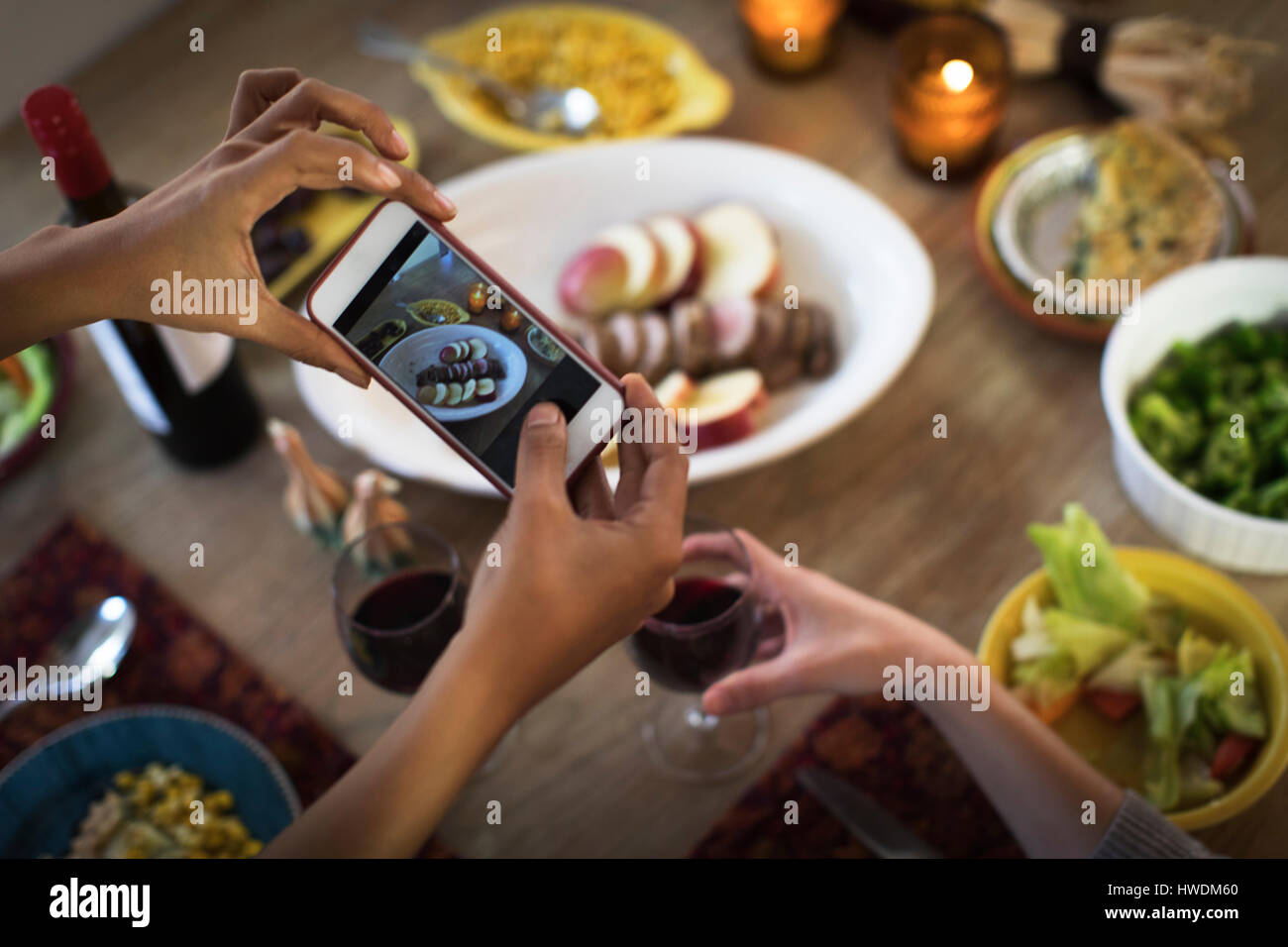 Hände von Freundinnen fotografieren Mahlzeit am Küchentisch Stockfoto