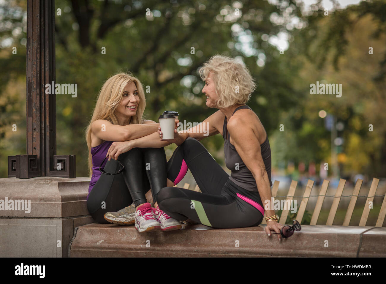 Zwei Reife Freundinnen training im Park, sitzen auf Wand mit Kaffee zum mitnehmen Stockfoto