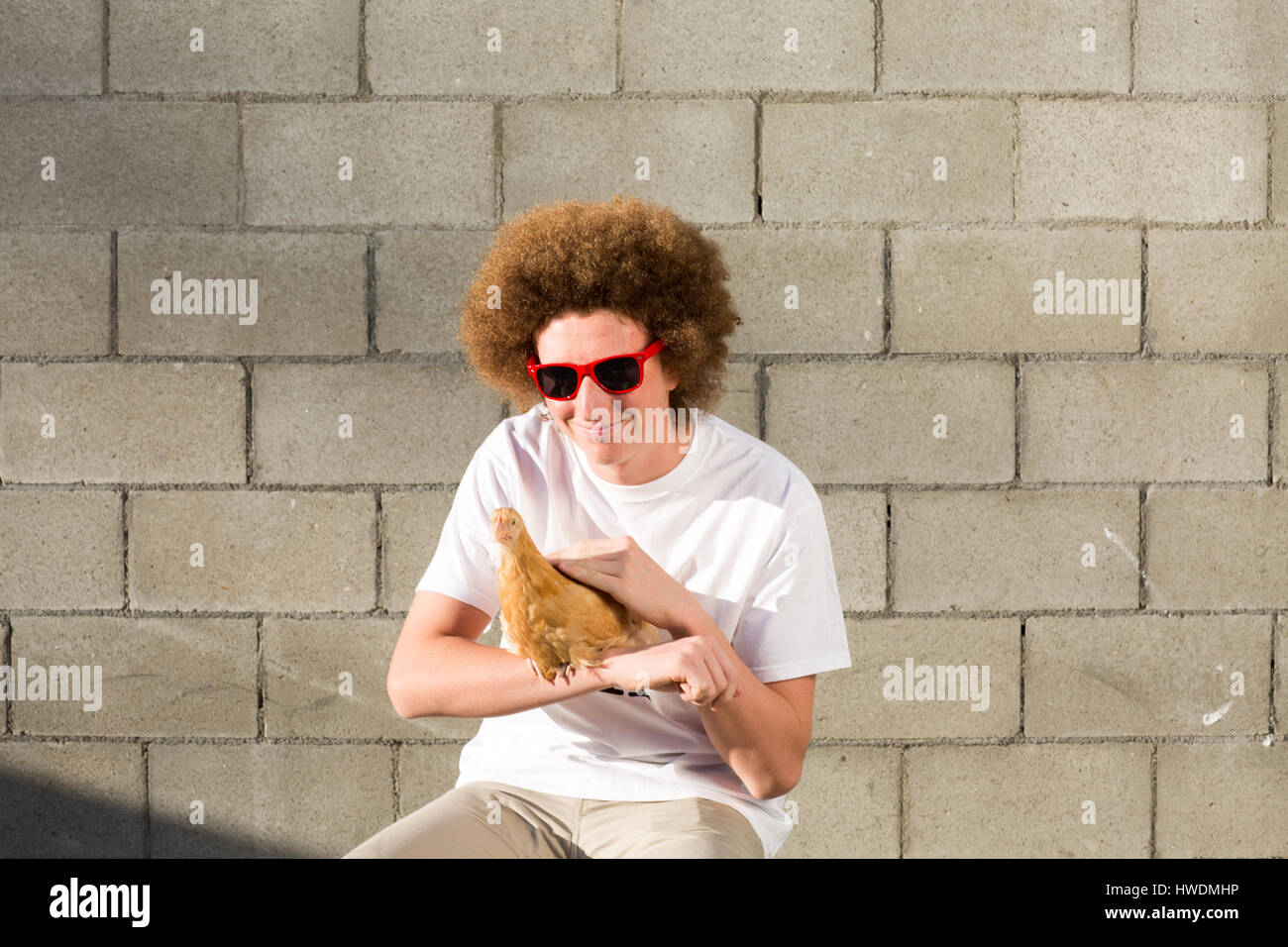 Porträt von Teenager mit roten Afro-Haar, mit Huhn Stockfoto