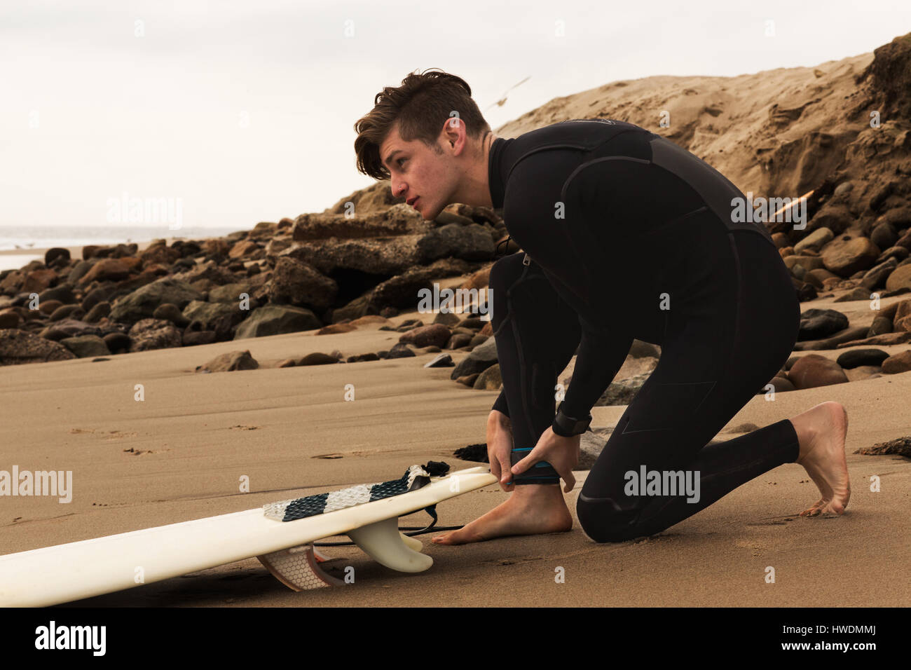 Junger Mann am Strand mit Surfbrett, Surfen wird vorbereitet Stockfoto
