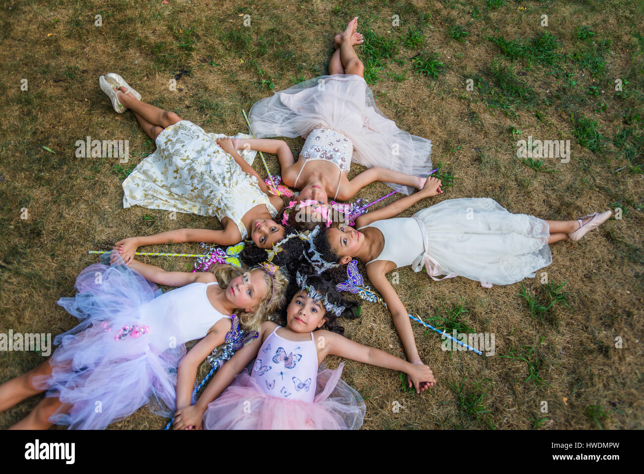 Gruppe junger Mädchen gekleidet wie Feen, liegen im Kreis, Köpfe zusammen Stockfoto