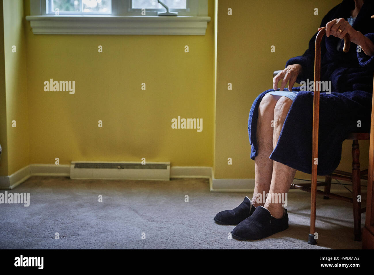Senior Frau sitzt im Stuhl, Spazierstock, niedrigen Bereich halten Stockfoto