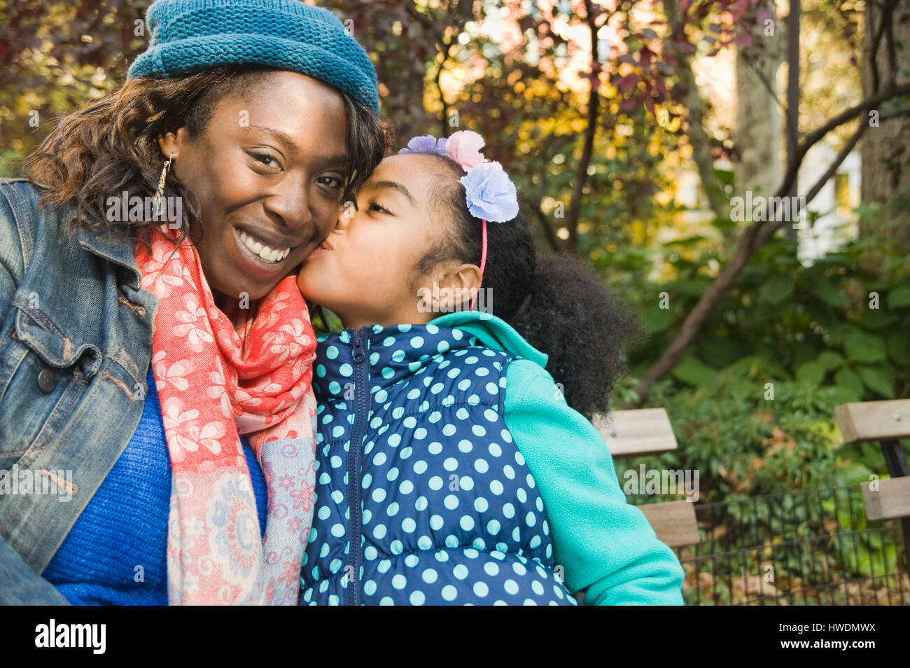 Tochter, die lächelnde Mutter auf Wange küssen Stockfoto