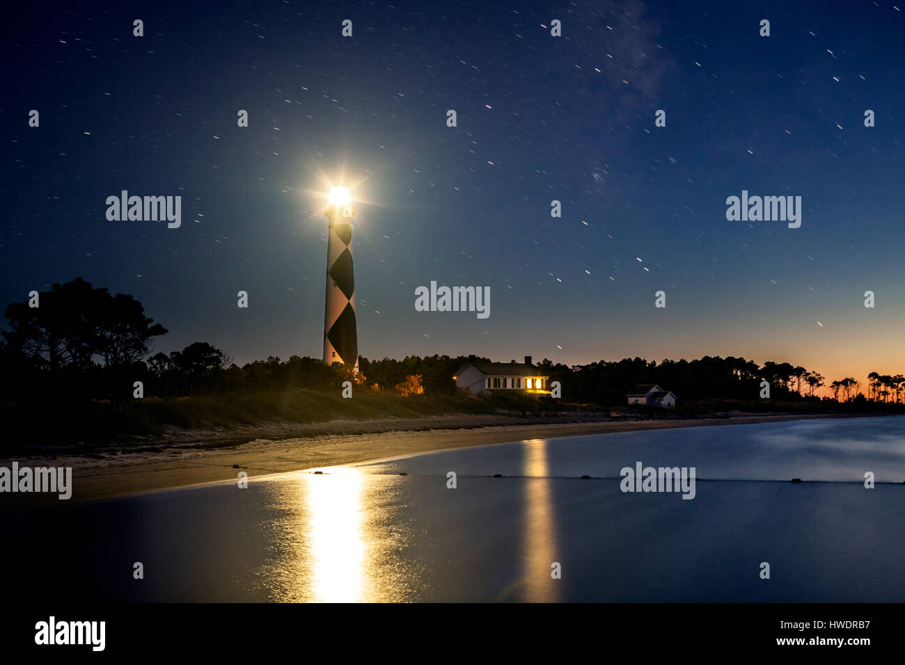 NC00882-00... NORTH CAROLINA - Cape Lookout Leuchtturm und Keepers Haus in Cape Lookout National Seashore spiegelt sich in Bardens Einlass in der Dämmerung. Stockfoto