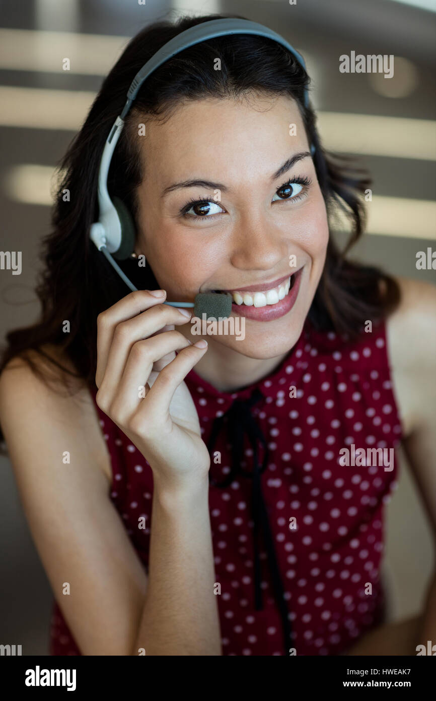 Lächelnde Kundenservice sprechen über Kopfhörer im Büro Stockfoto