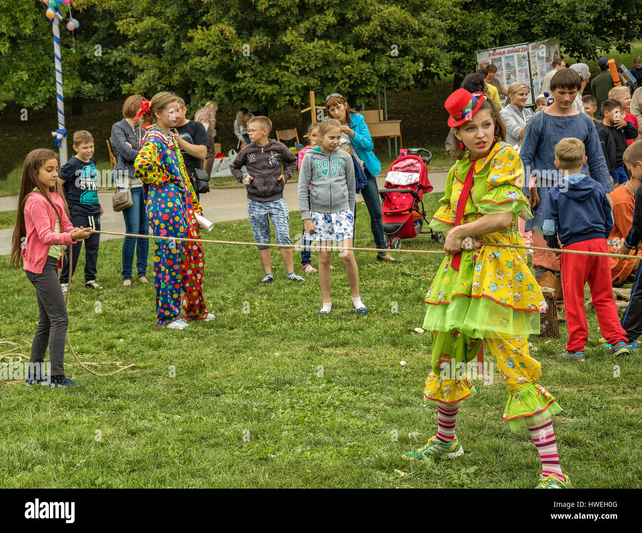 Kinder und gekleidet in Clown Kostüm eine Frau spielen an der frischen Luft Stockfoto