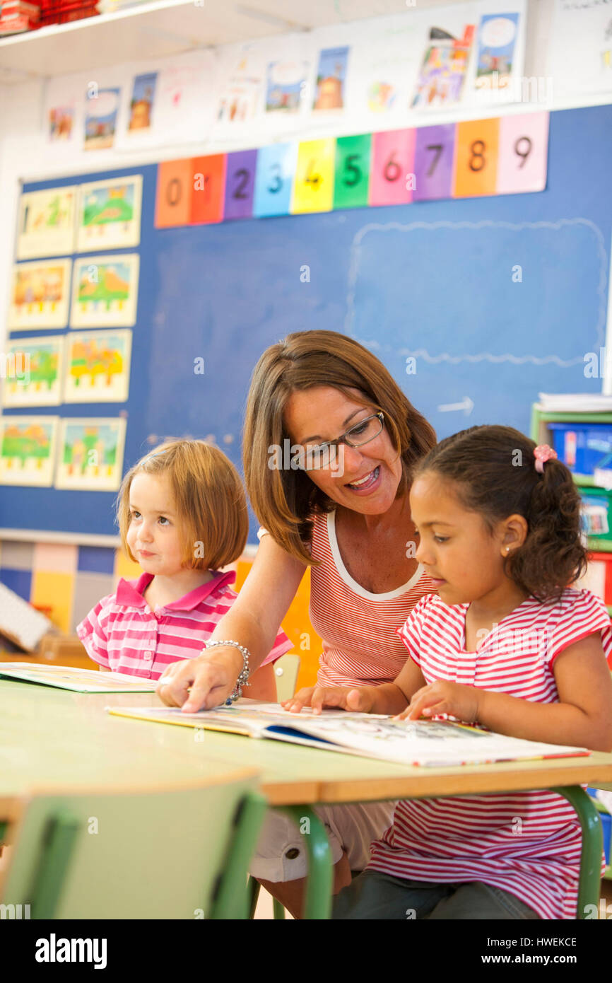 Kindergarten Mädchen und Lehrer lesen Märchenbuch im Klassenzimmer Stockfoto