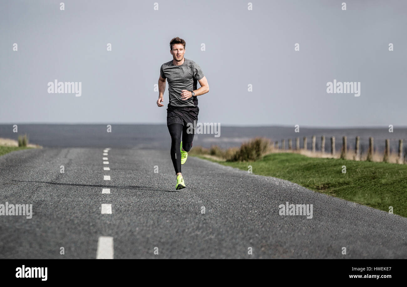 Männliche Läufer laufen entlang des ländlichen Raums Moorland road Stockfoto