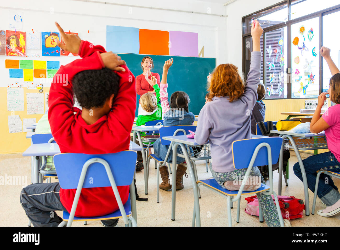 Rückansicht des primären Schülerinnen und Jungen mit Handzeichen im Klassenzimmer Stockfoto