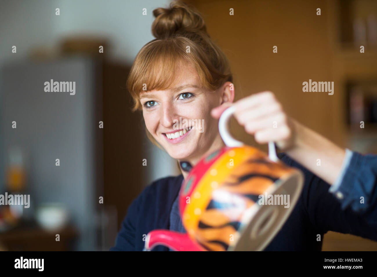 Junge Frau Gießen Tee von Teekanne Stockfoto
