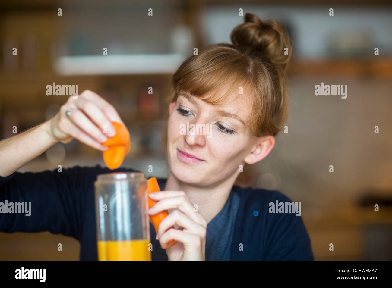 Junge Frau machen Smoothie mit frischen Karotten Stockfoto