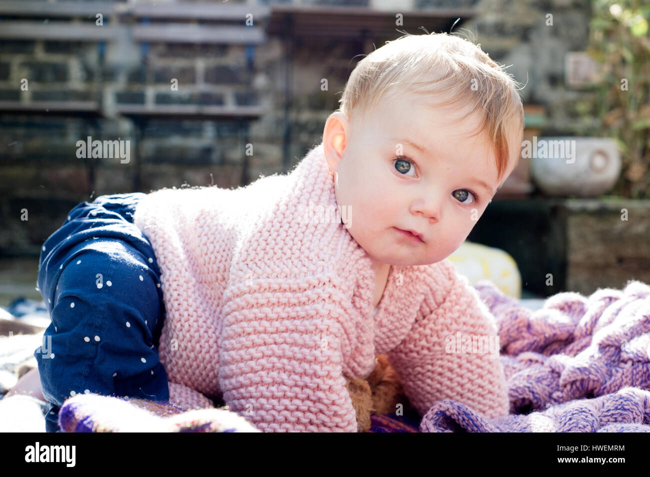 Porträt von Babymädchen kriecht auf gestrickte Decke im Garten Stockfoto