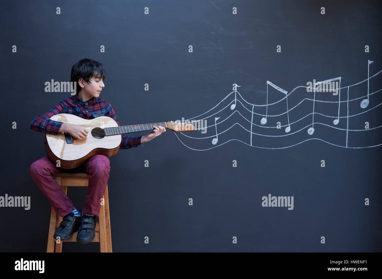 Junge, die Gitarre vor Tafel Wand mit Notenschrift anzeigen Stockfoto