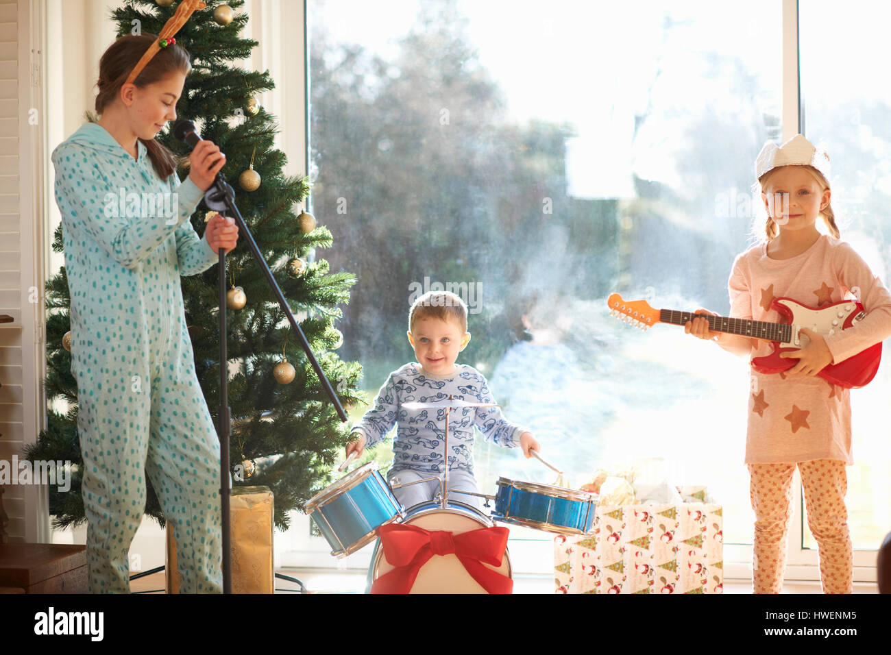 Junge und Schwestern spielen Spielzeug Schlagzeug und Gitarre am Weihnachtstag Stockfoto