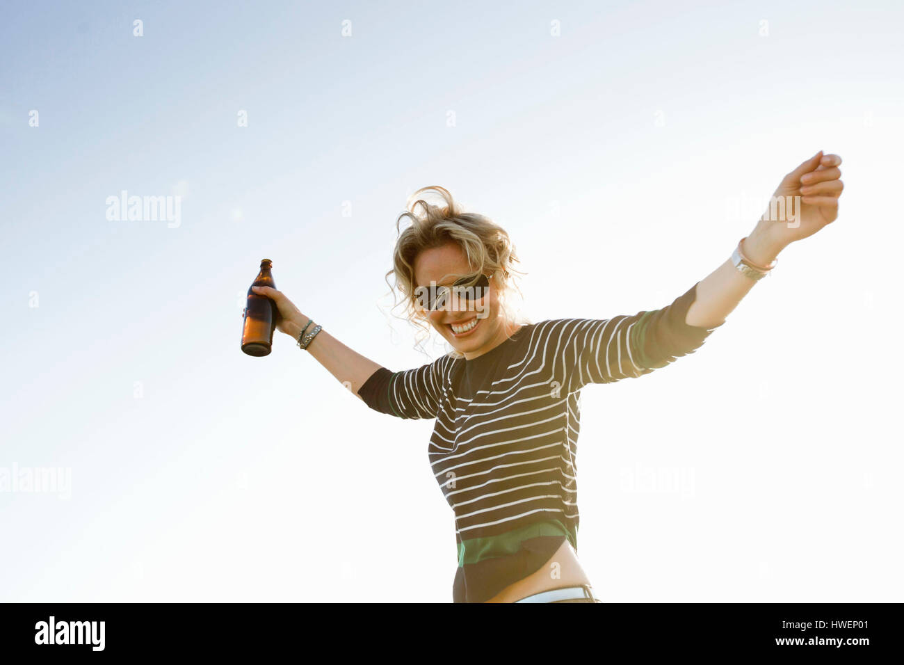 Porträt von Mitte Erwachsene Frau mit sonnigen blauen Himmel offenen Armen Stockfoto