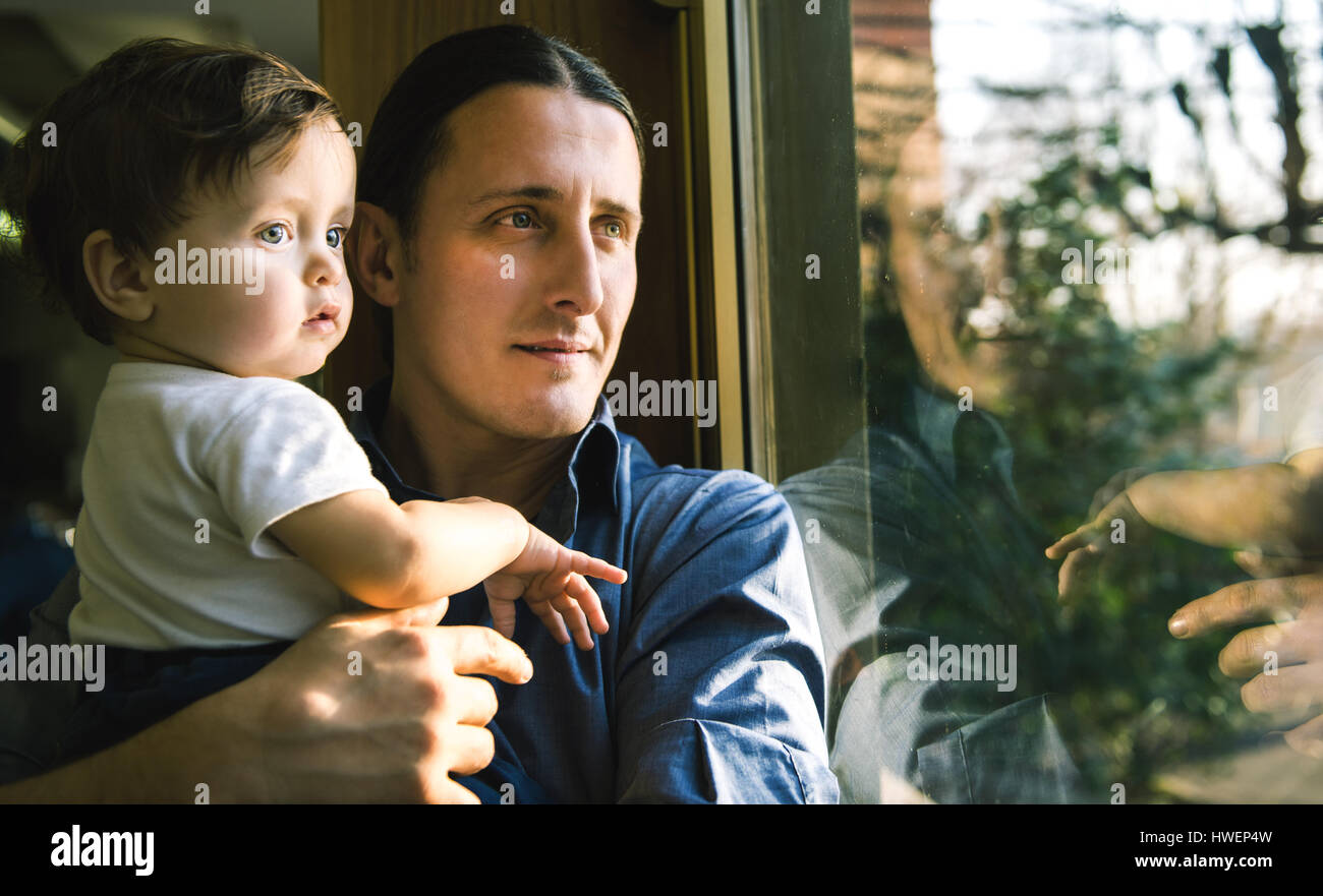 Reifer Mann und Baby Sohn Blick durch Fenster Stockfoto