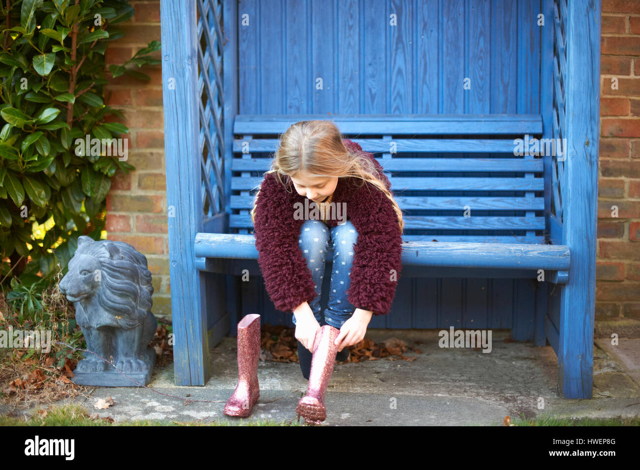 Mädchen Stiefel auf Laube Bank aufsetzen Stockfoto