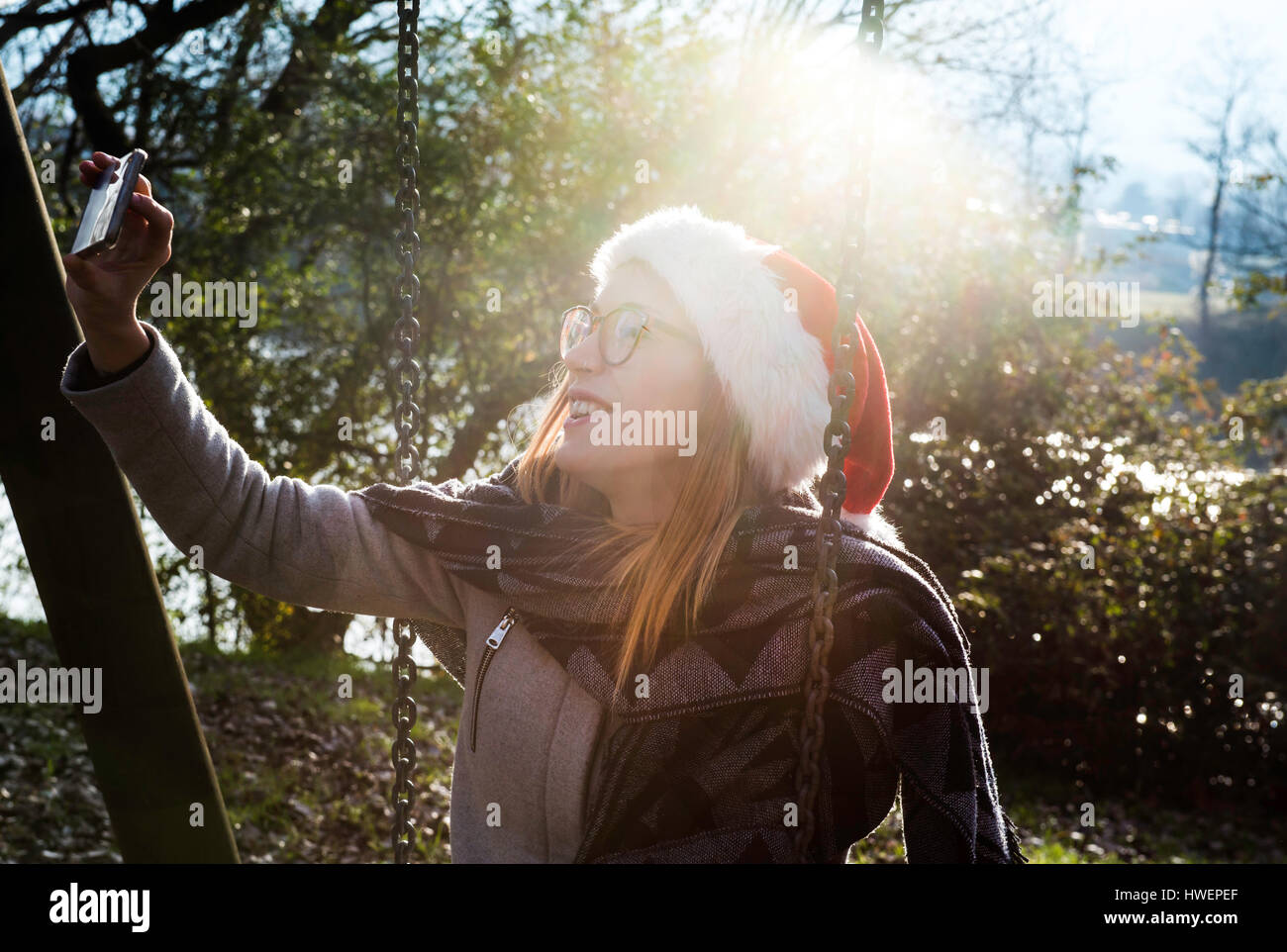 Junge Frau trägt, im Freien, Weihnachtshut trägt, wobei Selfie mit smartphone Stockfoto