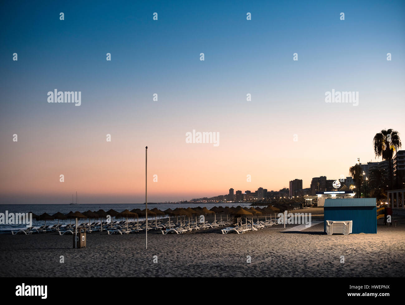 Sonnenliegen am Strand bei Sonnenuntergang, Fuengirola, Spanien Stockfoto