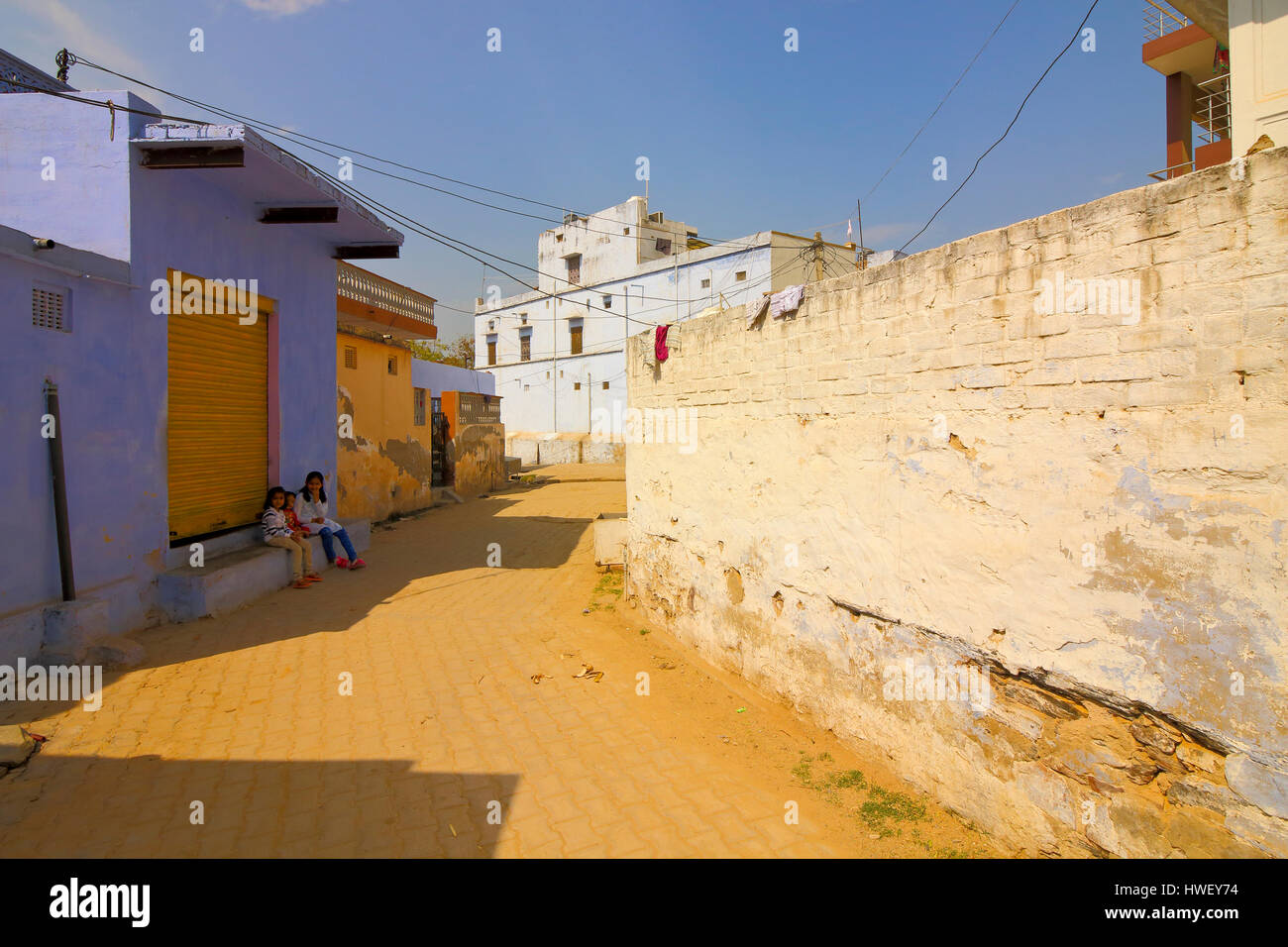 Kinder sitzen im Schatten der traditionellen Gebäude in einer Straße im Neemrana, Rajasthan, Nordindien. Stockfoto