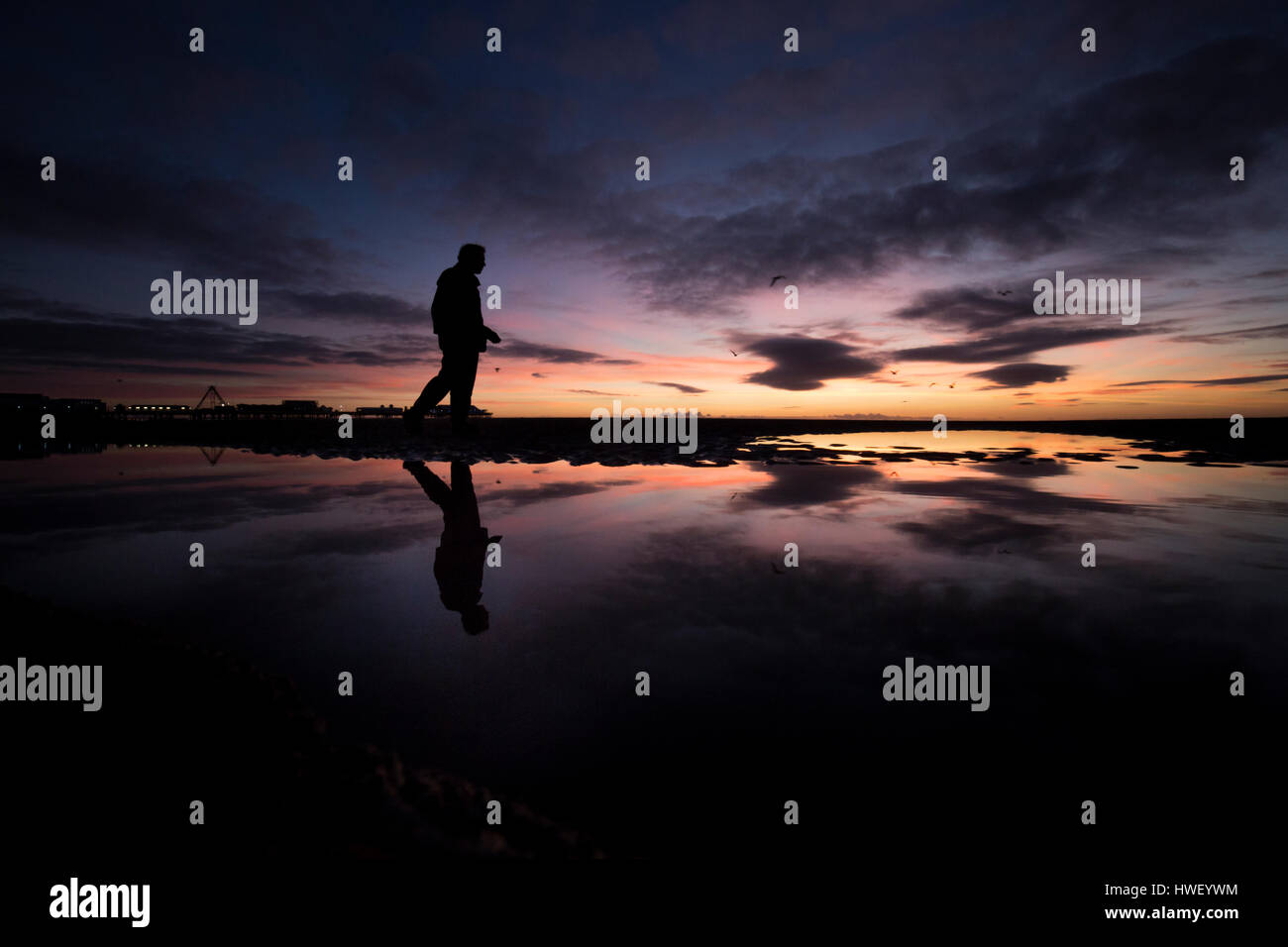 Blackpool - ein Badeort an der irischen See Englands. Die Silhouette eines Mannes spiegelt sich im Wasser am Strand. Stockfoto