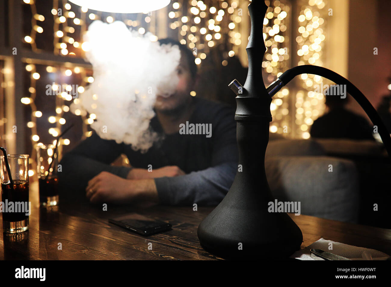 Mann hält Shisha Pfeife und Rauchen in einem Nachtclub Stockfoto