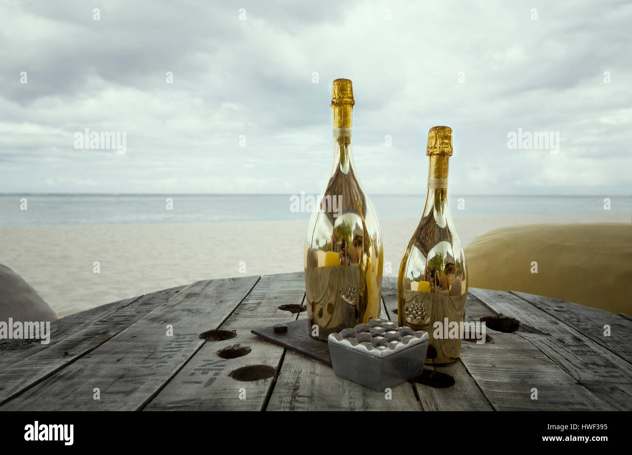 Zwei Flaschen Champagner auf einem alten Holztisch mit Hocker Sitze für romantisches Abendessen für Flitterwochen copules an einem tropischen Strand Stockfoto