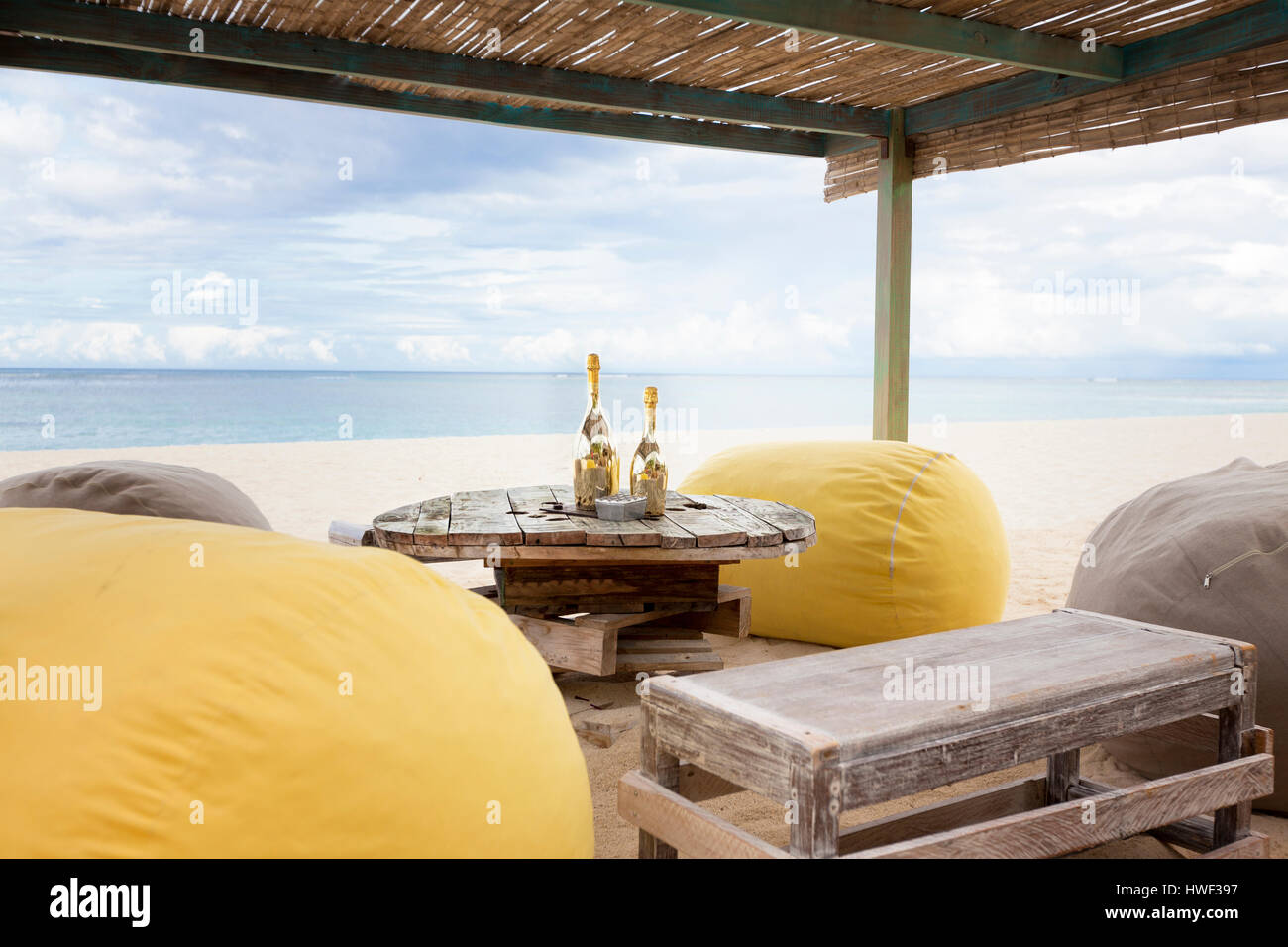 Zwei Flaschen Champagner auf einem alten Holztisch mit Hocker Sitze für romantisches Abendessen für Flitterwochen copules an einem tropischen Strand Stockfoto