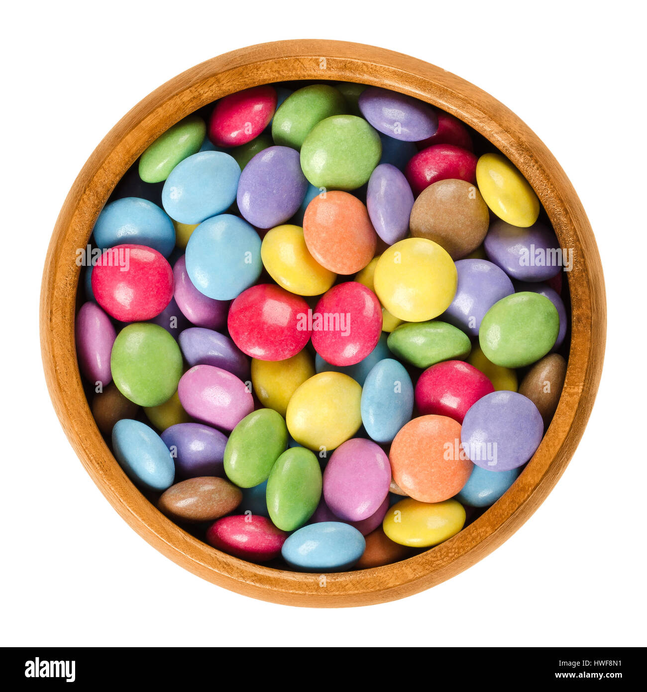 Bunte Pralinen in Holzschale. Zucker-beschichtete Schokoladenwaren in acht verschiedenen Farben. Oblate Spheroid Bonbons geformt. Stockfoto