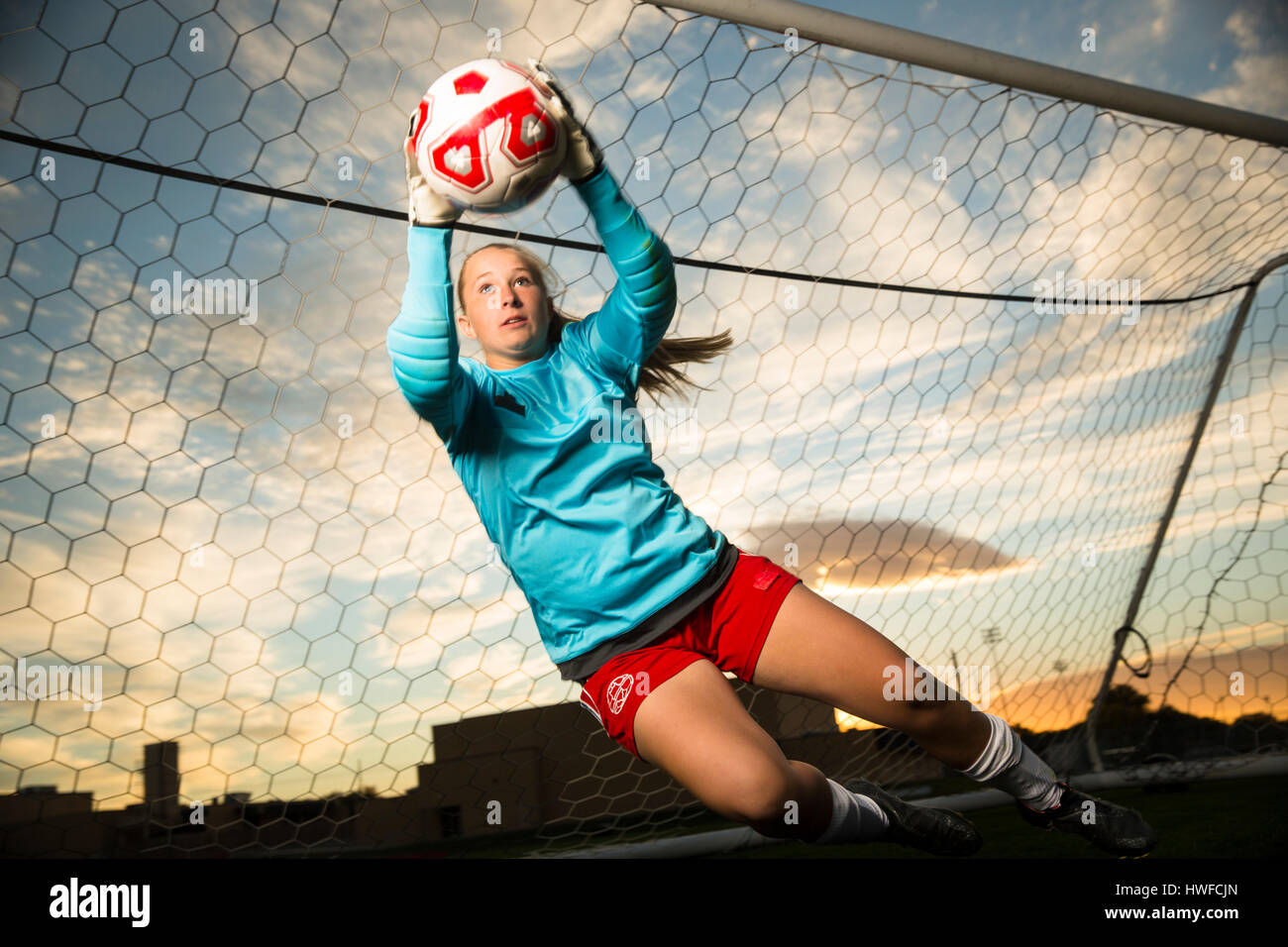 Niedrigen Winkel Blick auf Torwart springen und fangen Fußball Ball im Tor unter blauem Himmel Stockfoto