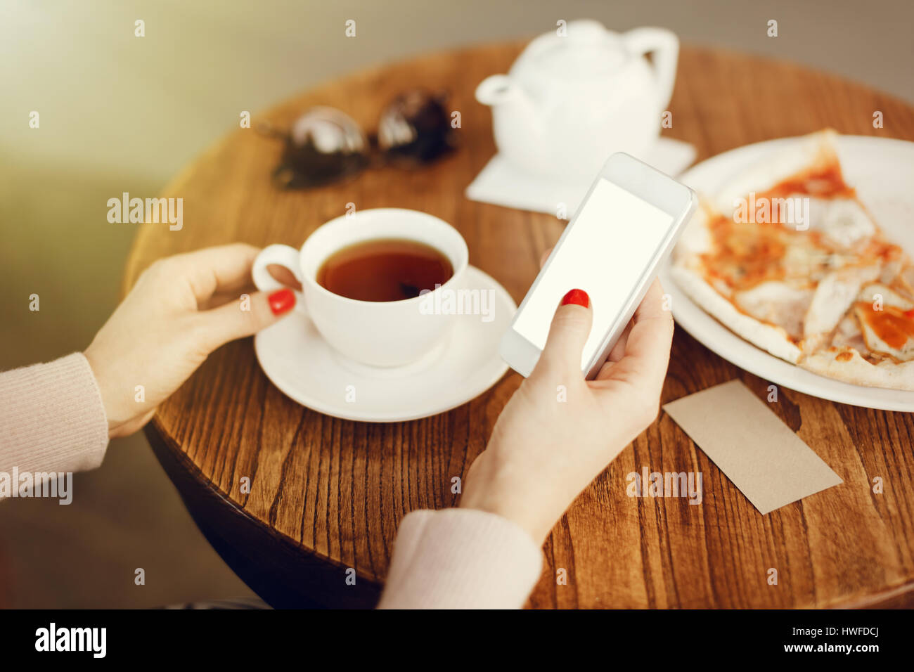 Mädchen hält Smartphone mit leeren Bildschirm im café Stockfoto