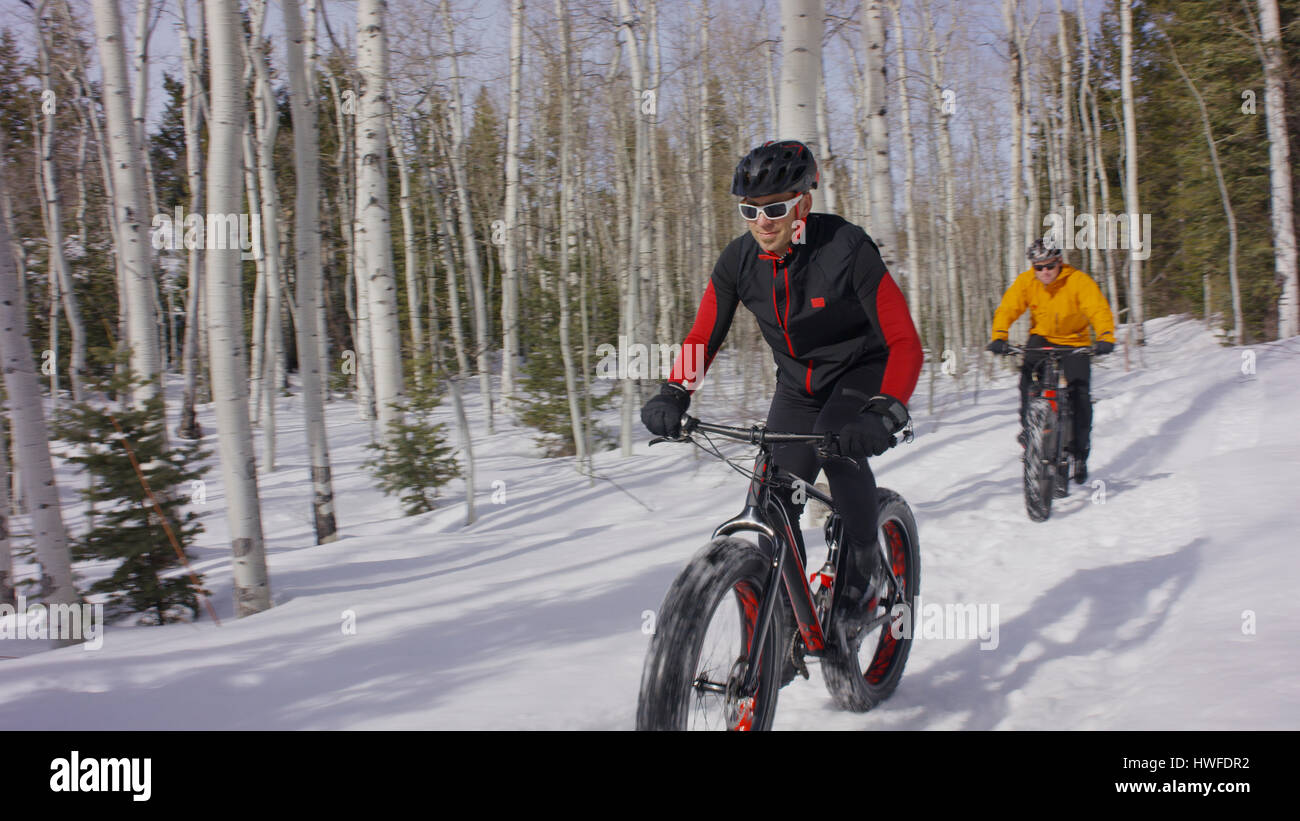 Männer reiten Mountain-Bikes in entfernten schneebedeckten Wald Stockfoto