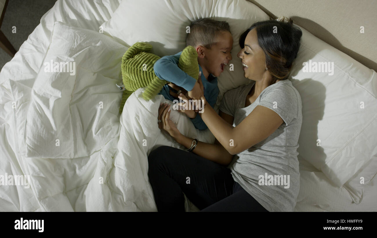 Hohen Winkel Höhenplan der Mutter kitzeln verspielt Sohn im Bett Stockfoto