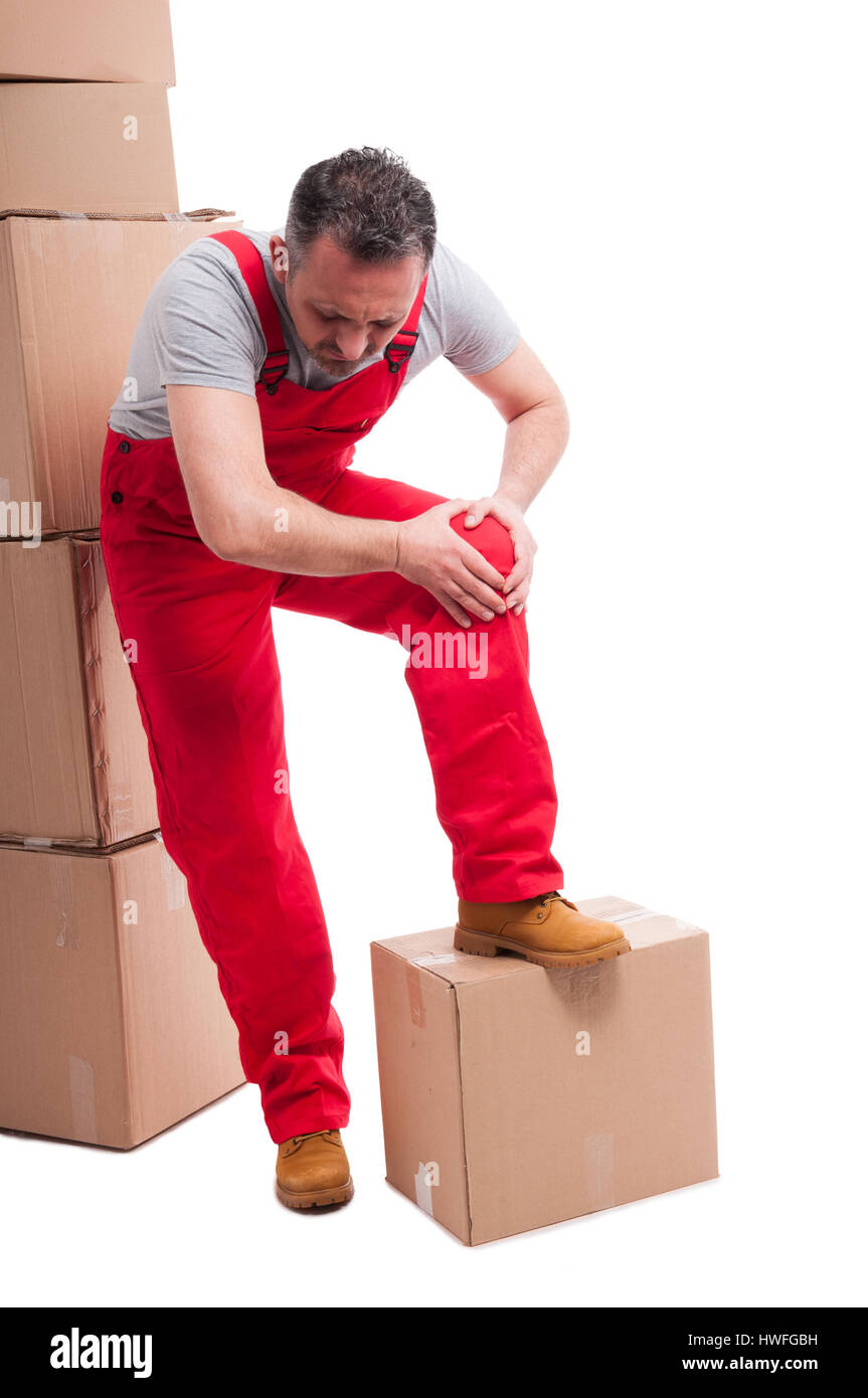 Ganzkörper von Mover Mann hält seine Knie wie weh mit Haufen Kartons um isoliert auf weißem Hintergrund Stockfoto