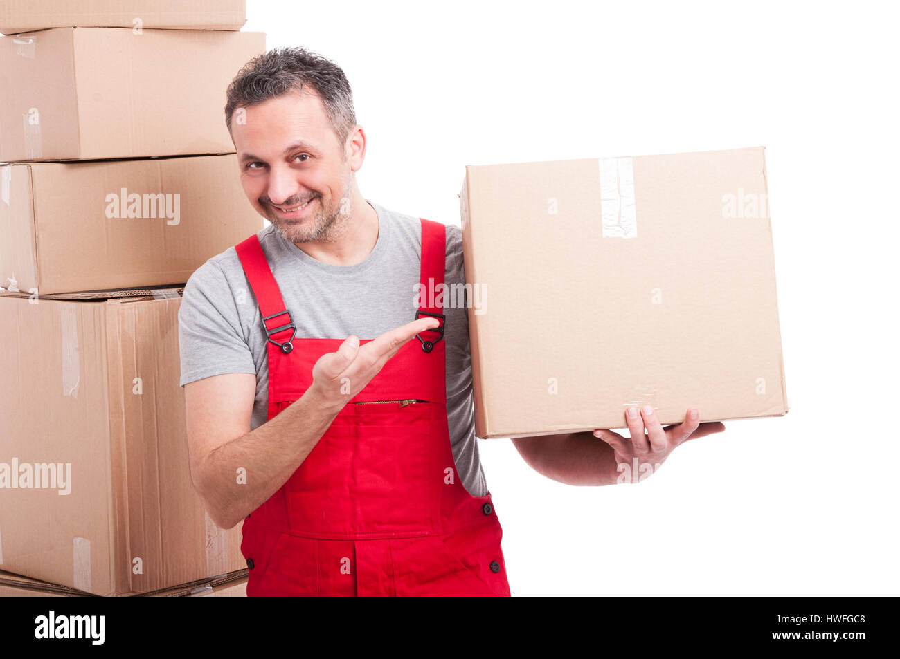 Mover Mann in rot, die insgesamt halten und zeigen einen großen Karton und lächelnd auf weißen Hintergrund isoliert Stockfoto
