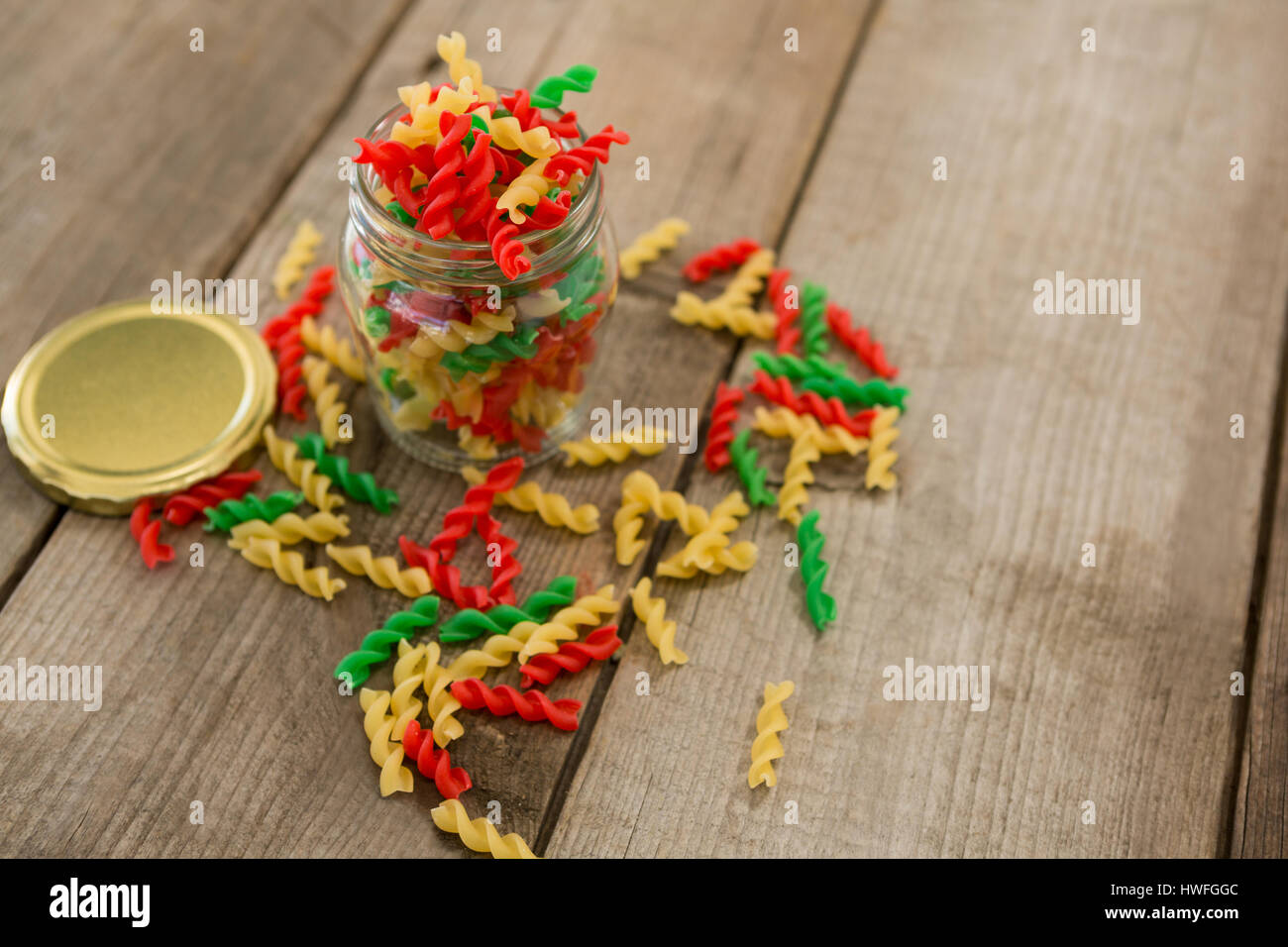 Glas gefüllt mit dreifarbige Rotini Pasta auf hölzernen Hintergrund Stockfoto