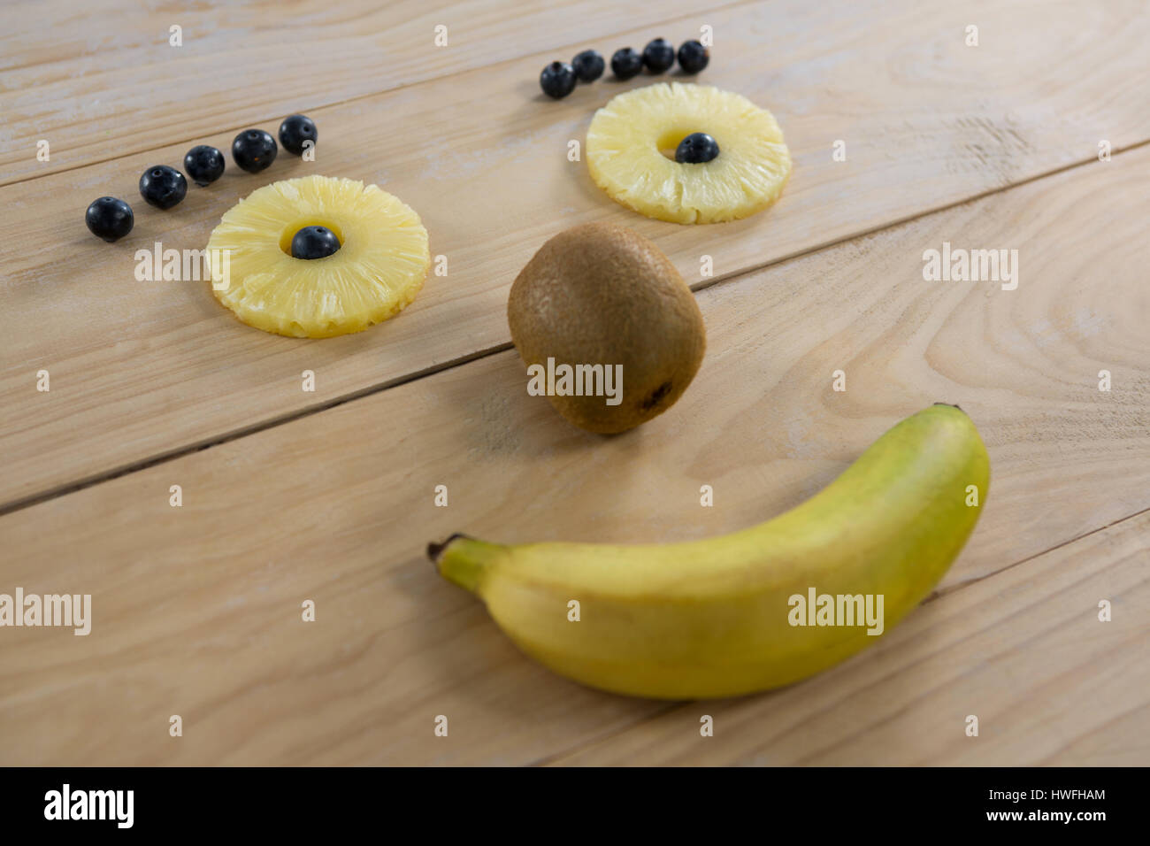 Verschiedene Früchte, angeordnet in Smiley-Gesicht auf Holztisch Stockfoto